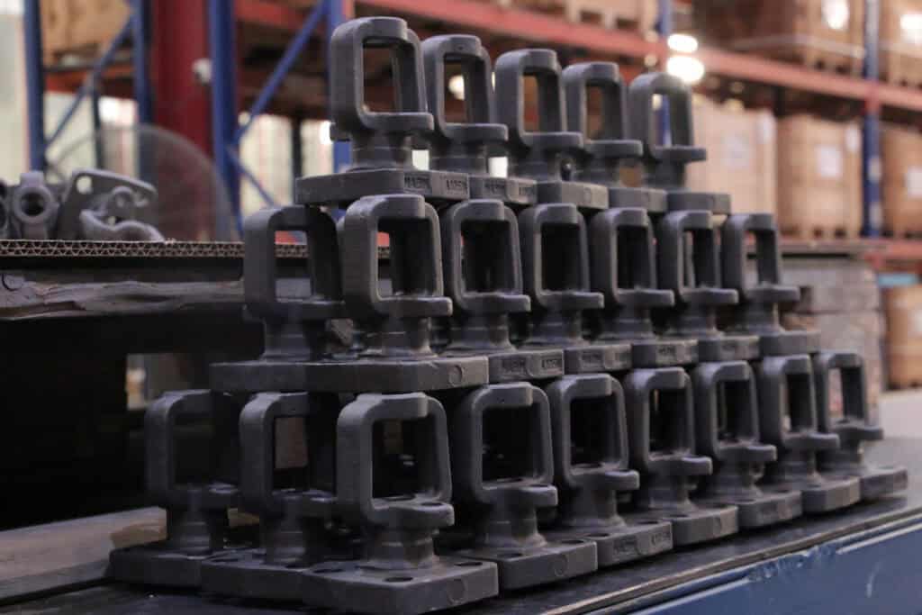 Steel clamp fixtures stacked in a warehouse or manufacturing setting for industrial use.